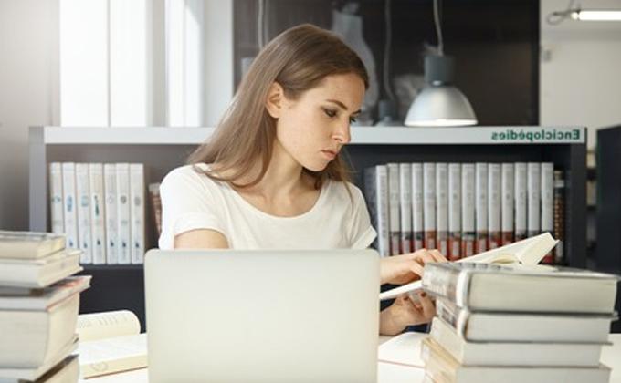 woman looking over textbook at desk