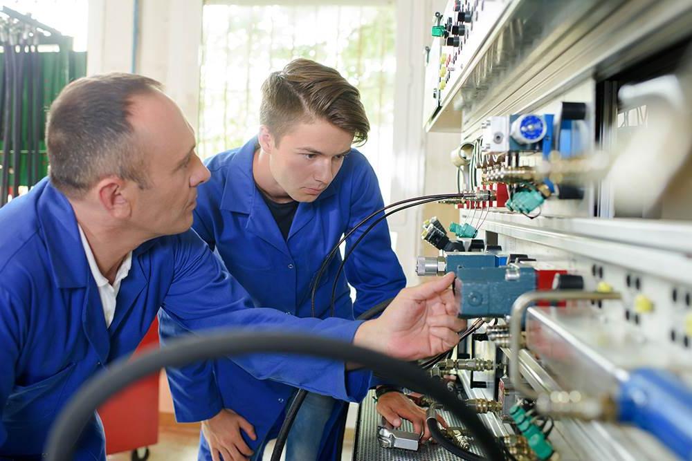 Two men in lab coats looking at electrical circuits